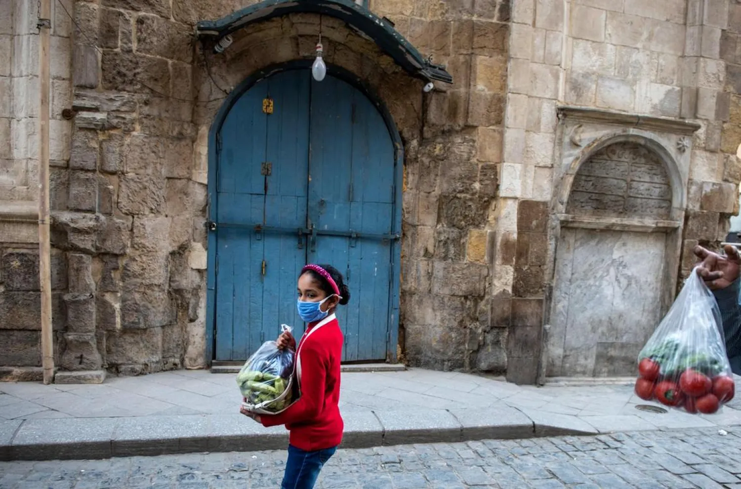 A child wearing face mask walks in front of closed shops shortly before lockdown, in Cairo, Egypt. (EPA)