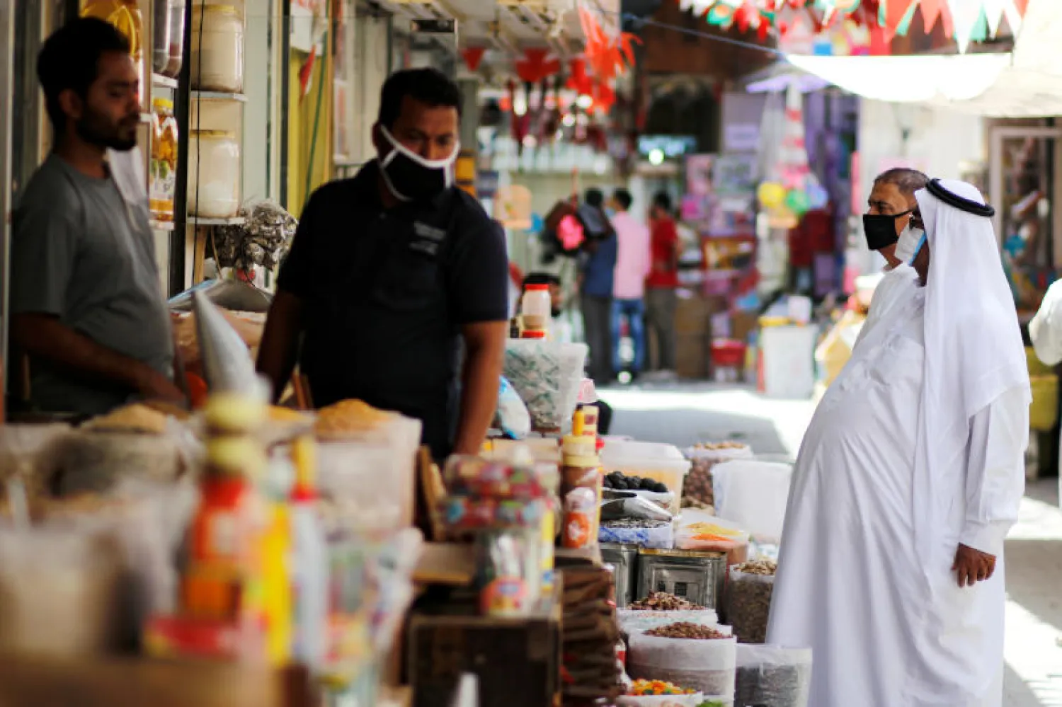 متسوقون بحرينيون يرتدون أقنعة واقية في إحدى أسواق المنامة (رويترز)