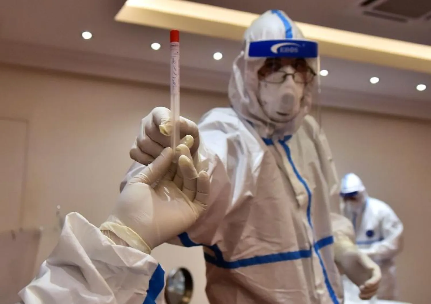 أحد أفراد الطاقم الطبي في لبنان يحمل اختباراً للدم (أ.ف.ب)