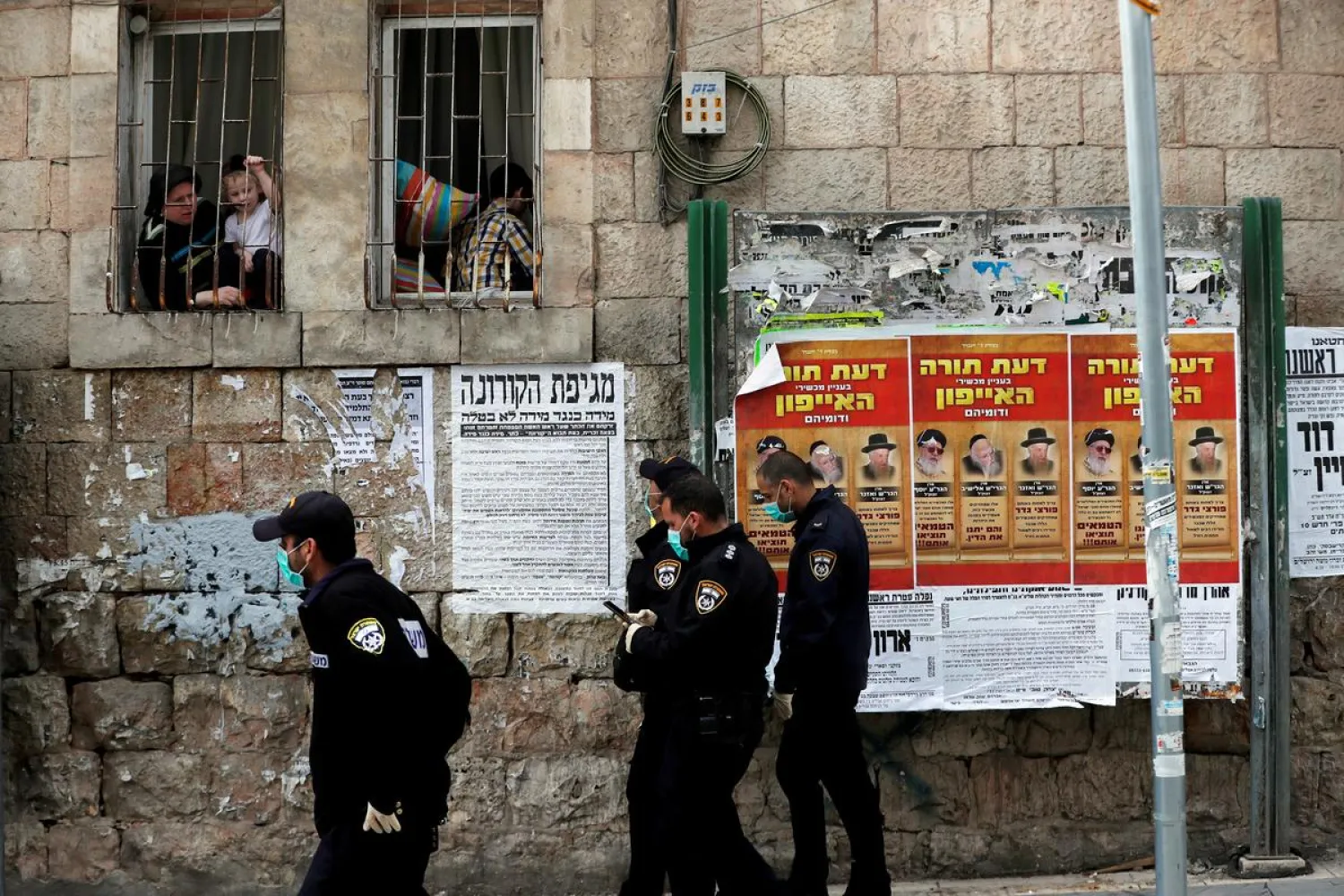 FILE PHOTO: Israeli policemen wearing masks talk to residents from their window as they enforce government restrictions placed to curb the spread of the coronavirus disease (COVID-19) in Mea Shearim neighborhood of Jerusalem March 26, 2020. REUTERS/Ronen Zvulun/File Photo