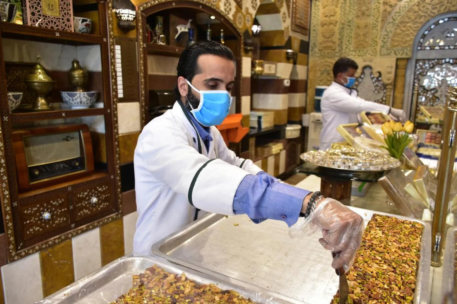A vendor wearing face mask sells sweets at al-Midan neighborhood ahead of the month of Ramadan in Damascus, Syria. (EPA)