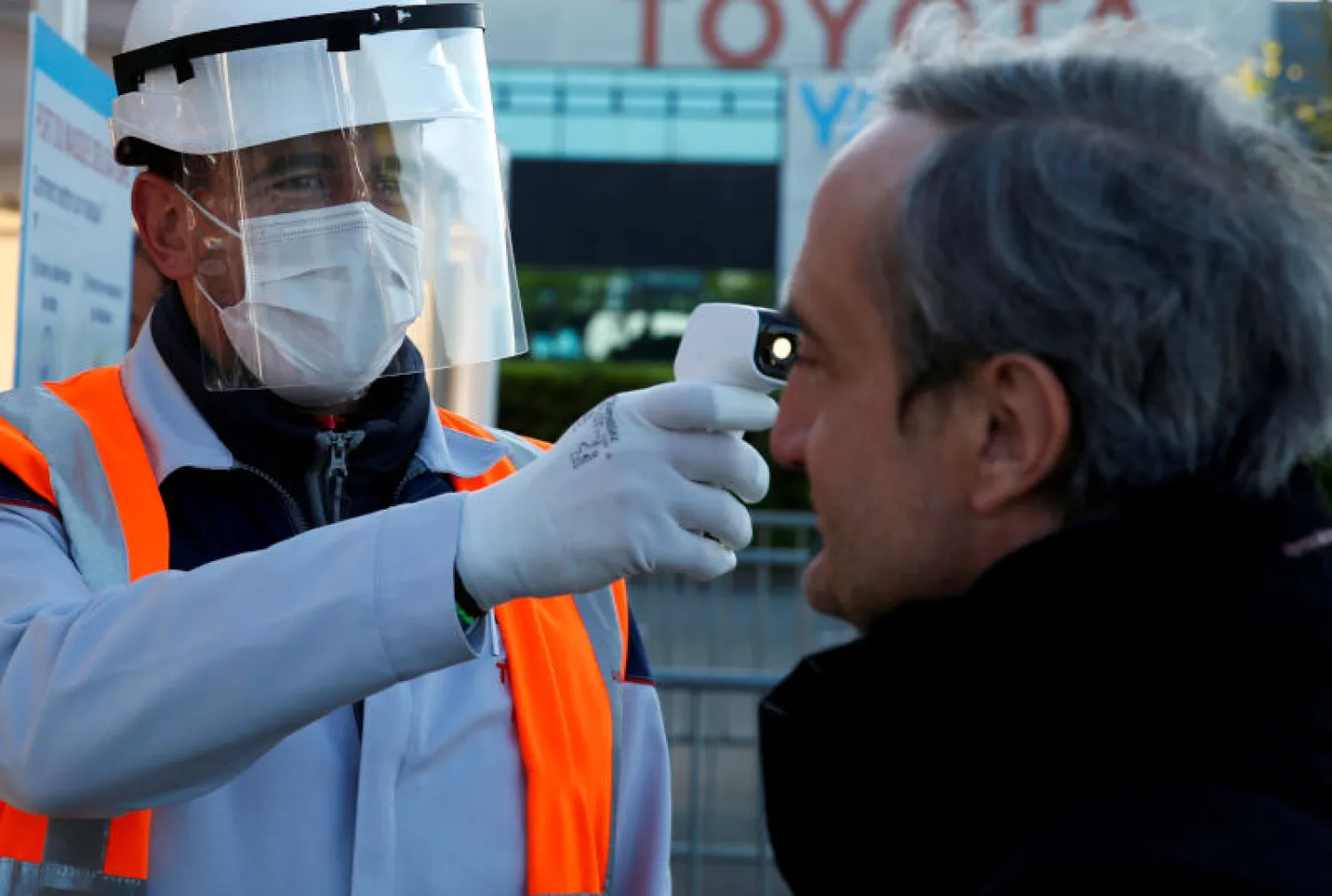 موظف يفحص حرارة أحد العمال خوفاً من فيروس كورونا في أحد مصانع شركة «تويوتا» بفرنسا (رويترز)