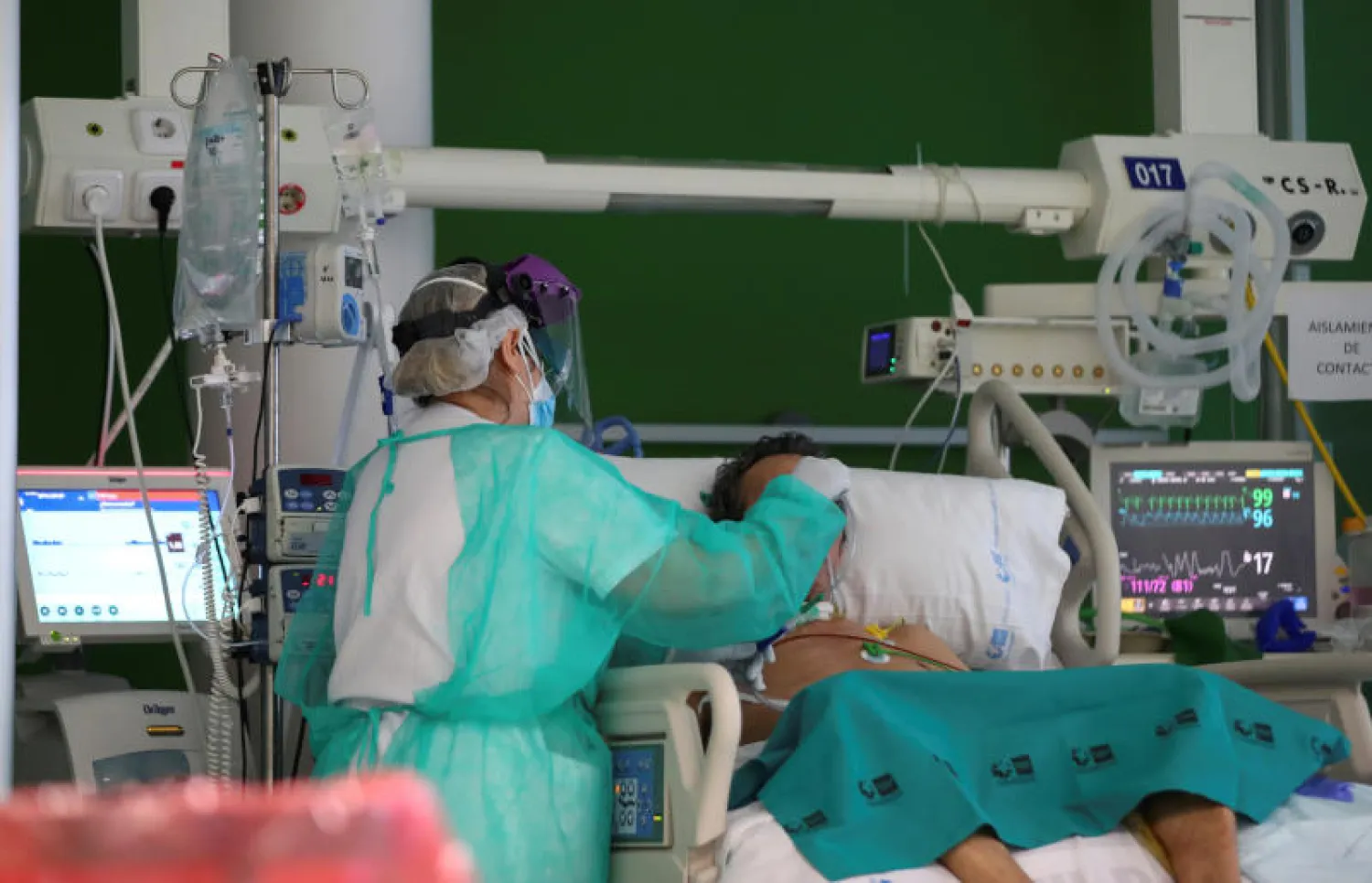 ممرضة تهتم بمريض مصاب بفيروس كورونا في أحد مستشفيات مدريد (رويترز)