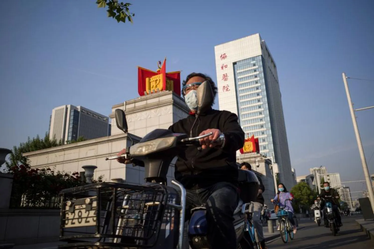 رجل يرتدي كمامة خلال قيادته دراجة في مدينة ووهان الصينية بؤرة تفشي فيروس كورونا (أ.ف.ب)