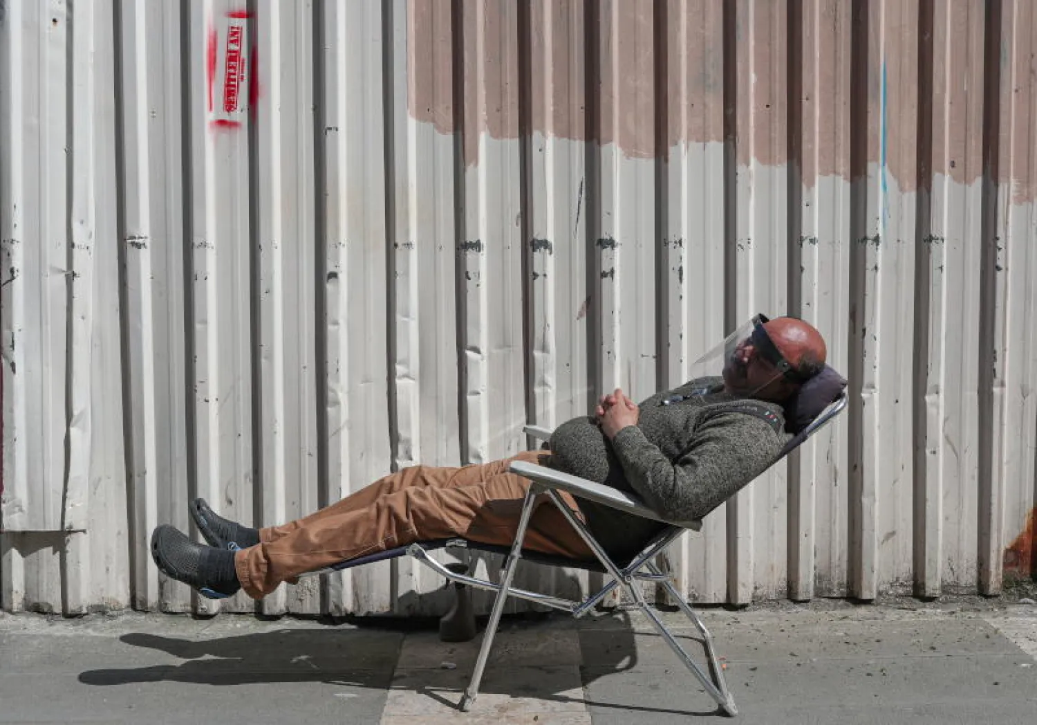 رجل يضع قناعاً واقياً على وجهه خوفاً من فيروس «كورونا» بينما ينام في أحد شوارع إسطنبول (إ.ب.أ)