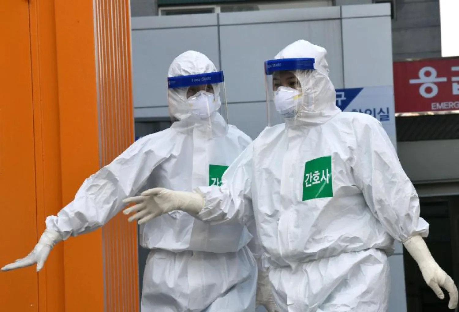 ممرضتان كوريتان جنوبيتان ترتديان الملابس الواقية قبل البدء بعملهما في رعاية مرضى «كورونا» (أ.ف.ب)