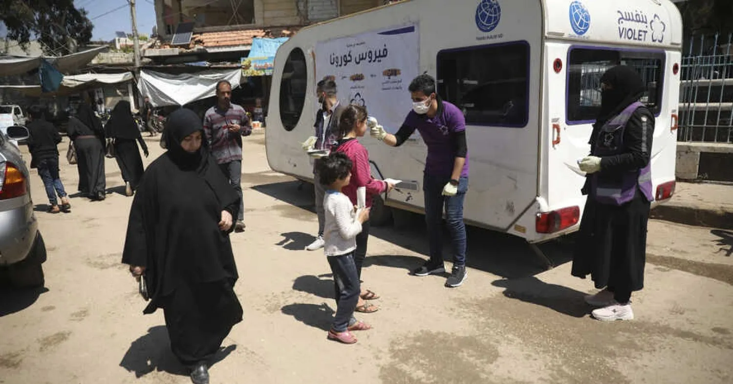 A member of a non-governmental aid organization measures temperature as a preventive measure for coronavirus in the town of Kafr Takharim, Idlib province, Syria, April 14, 2020. AP