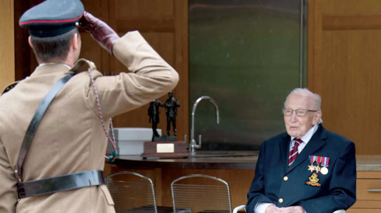 عقيد من الجيش يؤدي التحية للكابتن توم بعد أن سلمه خطاب منحه رتبة «كولونيل» الشرفية أمس (إ.ب.أ)