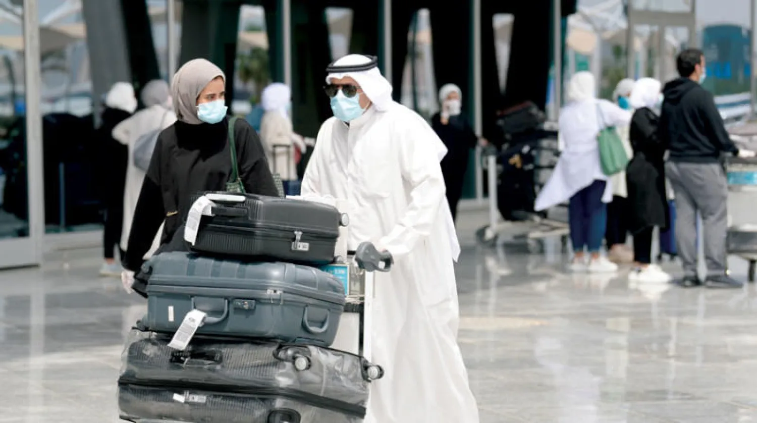 كويتيون لدى عودتهم إلى مطار الكويت الدولي (إ.ب.أ)