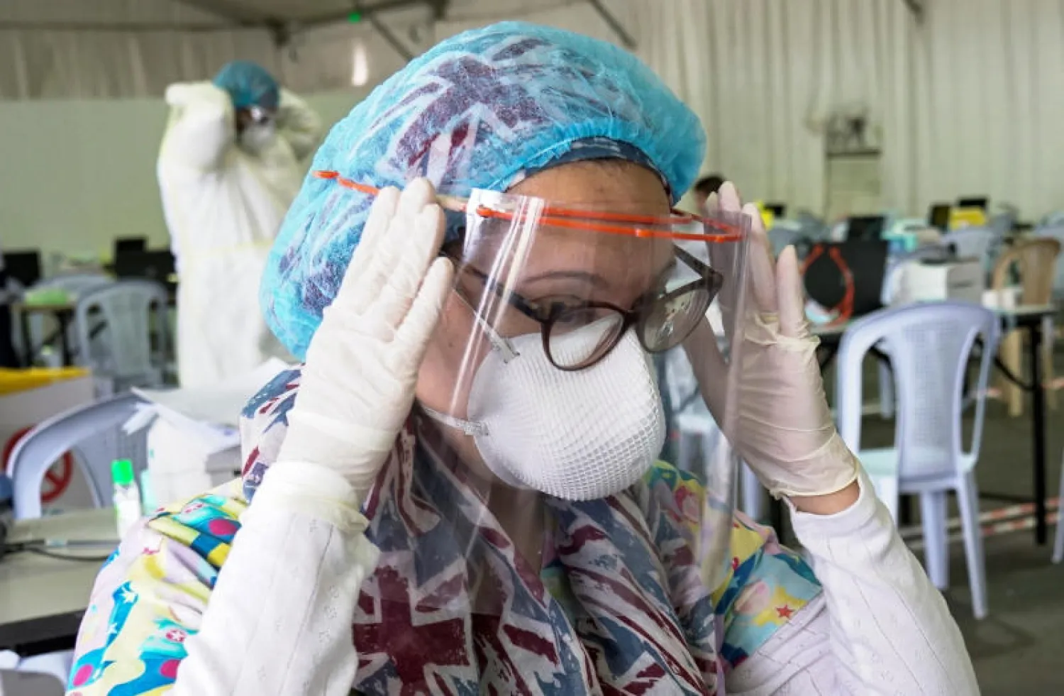 طبيبة كويتية تضبط قناعها الواقي في مركز مؤقت لاختبارات فيروس كورونا بمطار الكويت (أرشيفية - رويترز)