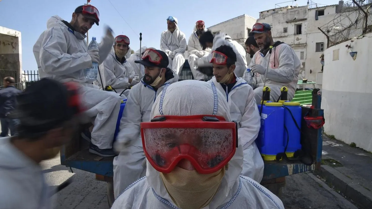 Municipal workers dressed in protective gear rest while on duty disinfecting a street during the COVID-19 pandemic in the Bab el-Oued district of Algeria's capital Algiers on April 9, 2020. (AFP)