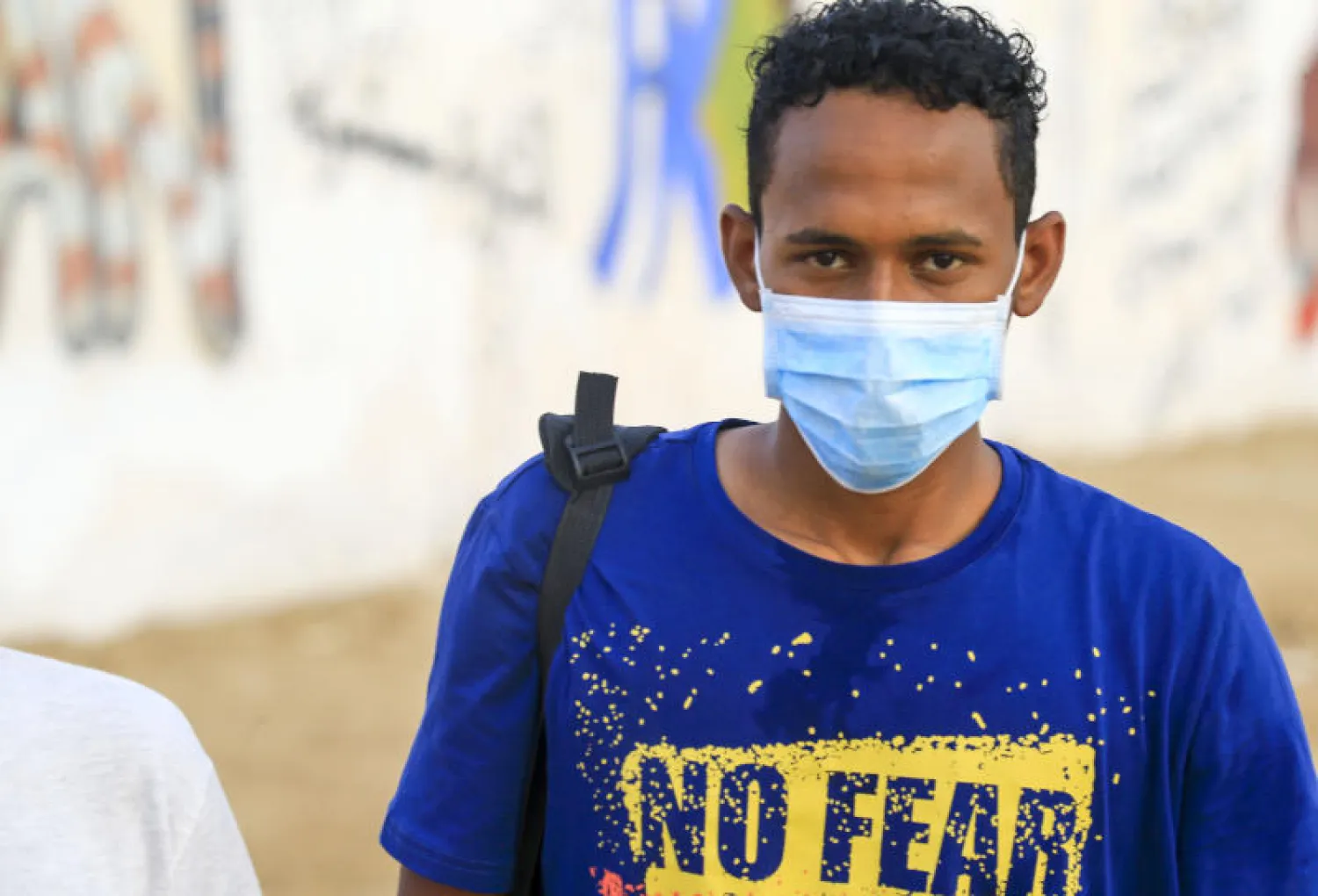 متطوع سوداني يرتدي كمامة خلال حملة توعية للوقاية من كورونا في أحد شوارع الخرطوم (أ.ف.ب)