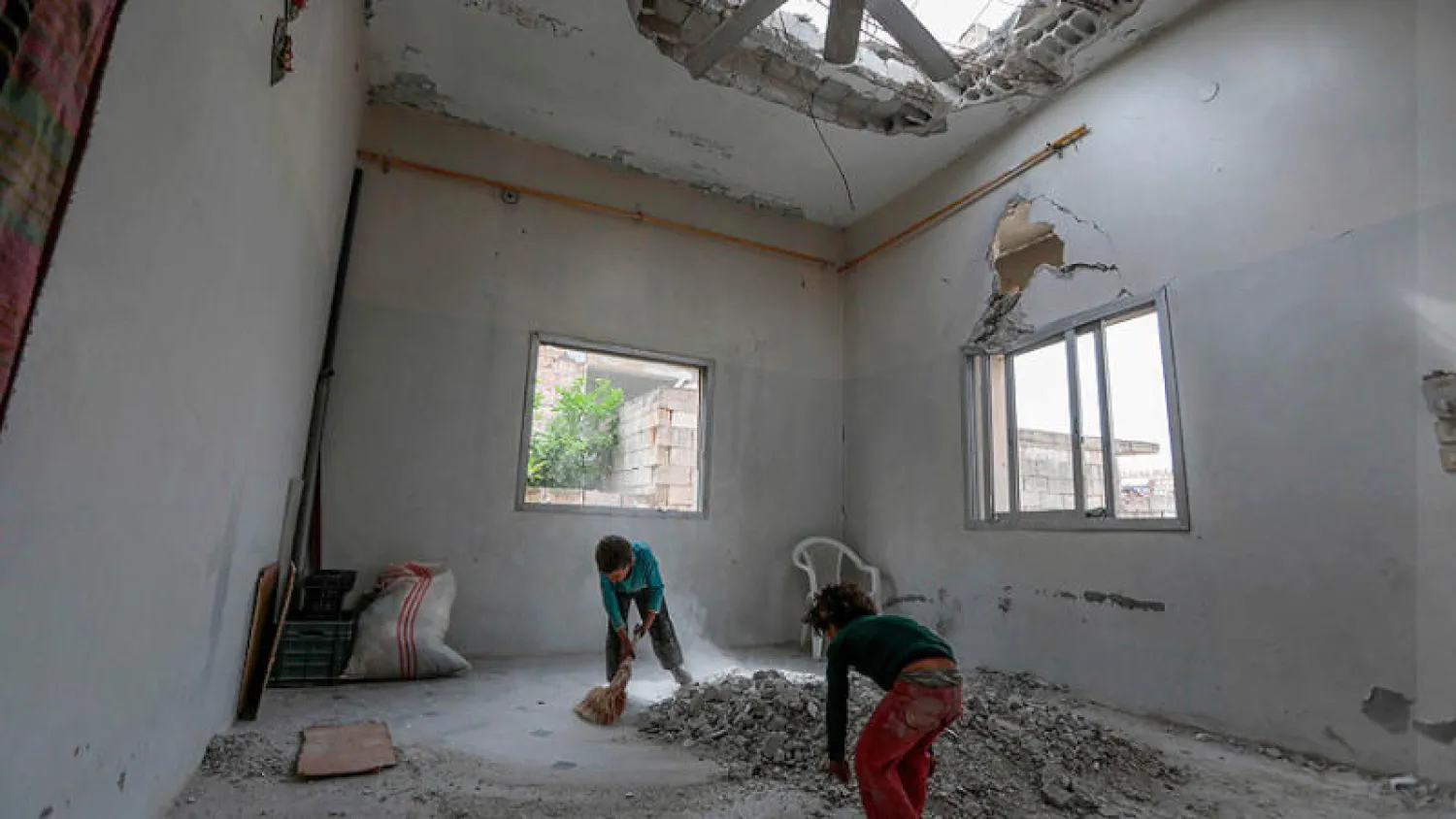 صبيان يزيلان الأنقاض من منزل عائلتهما العائدة إلى النيرب بمحافظة إدلب شمال غربي سوريا (أ.ف.ب)