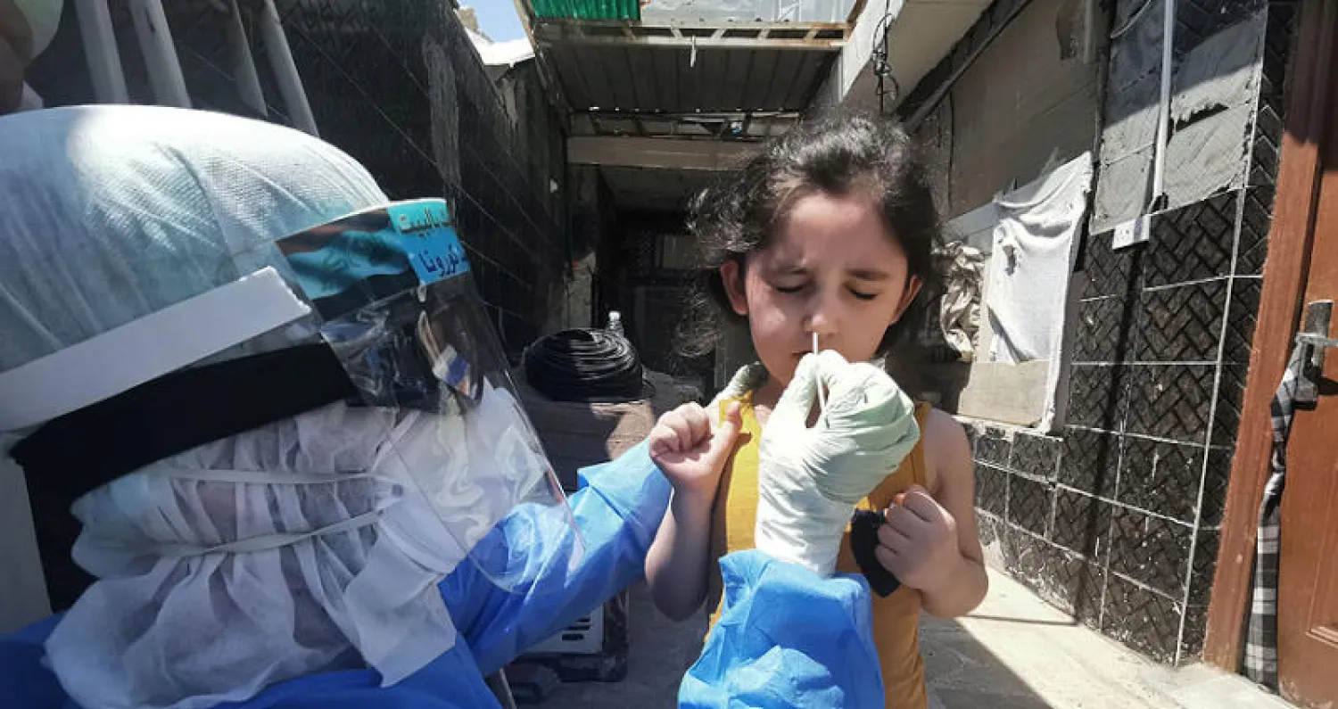 عاملة صحة تخضع طفلة لفحص {كورونا} في النجف الثلاثاء الماضي (رويترز)