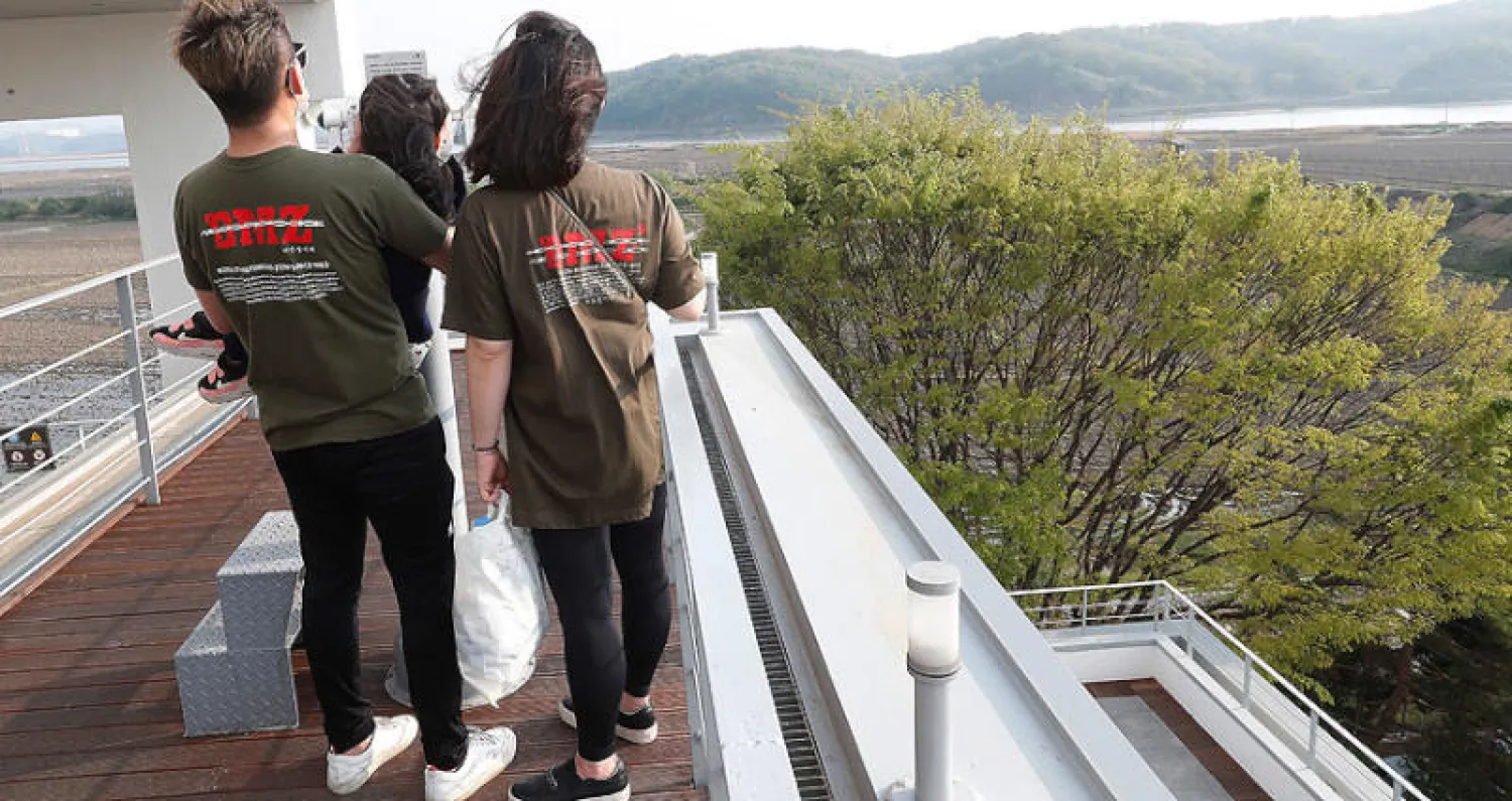 عائلة كورية جنوبية في منطقة باجو الحدودية تنظر أمس باتجاه الشمال حيث بدأ إطلاق النار (أ.ب)