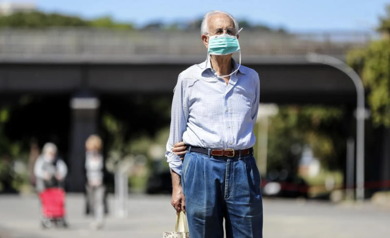 رجل مسنّ يرتدي قناعاً واقياً خلال تجوله في أحد شوارع روما (إ.ب.أ)