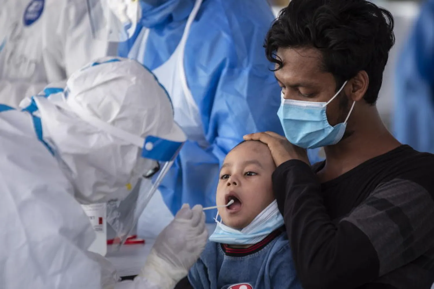 فريق طبي يفحص طفلاً في ماليزيا خلال تفشي فيروس «كورونا» (إ.ب.أ)