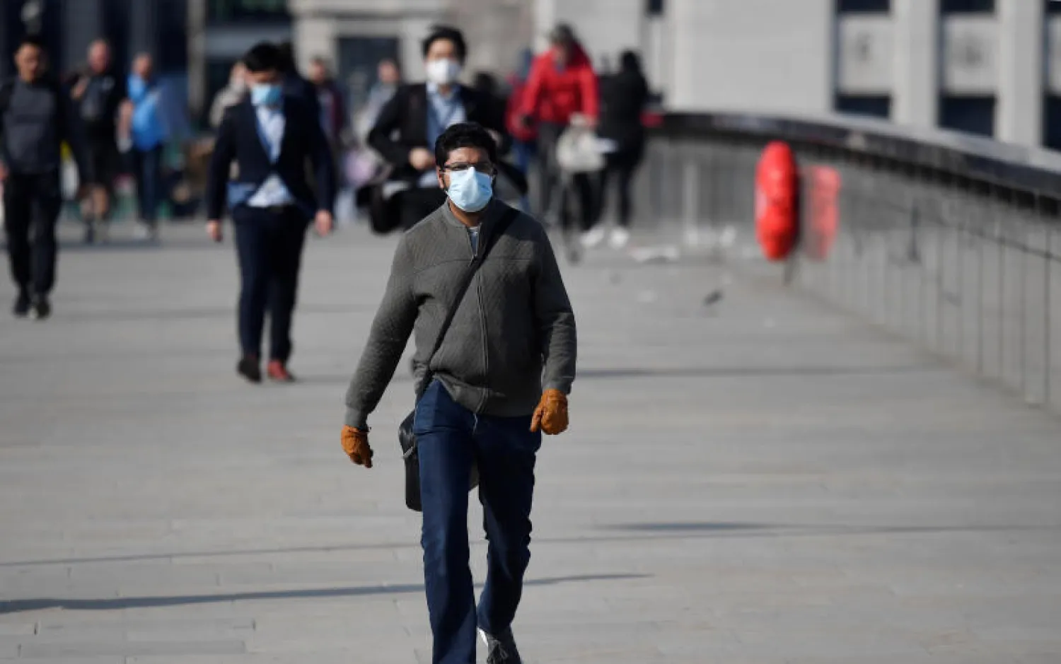 أشخاص يرتدون أقنعة واقية على جسر لندن (رويترز)