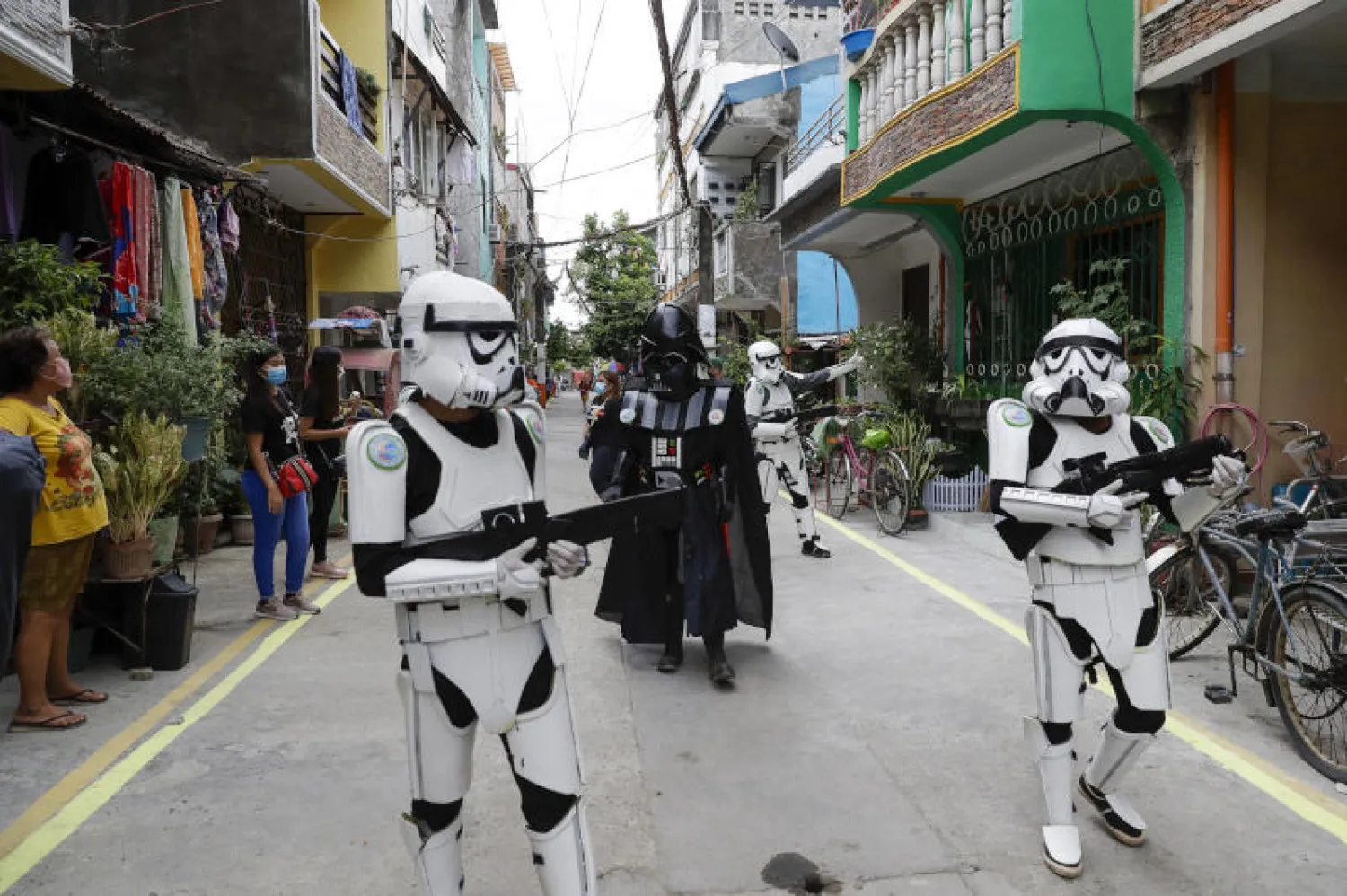 أعضاء مجموعة شبابية يرتدون أزياء حرب النجوم ويرفهون عن السكان المحليين على طول طريق في مالابون بالفلبين (أ.ب)