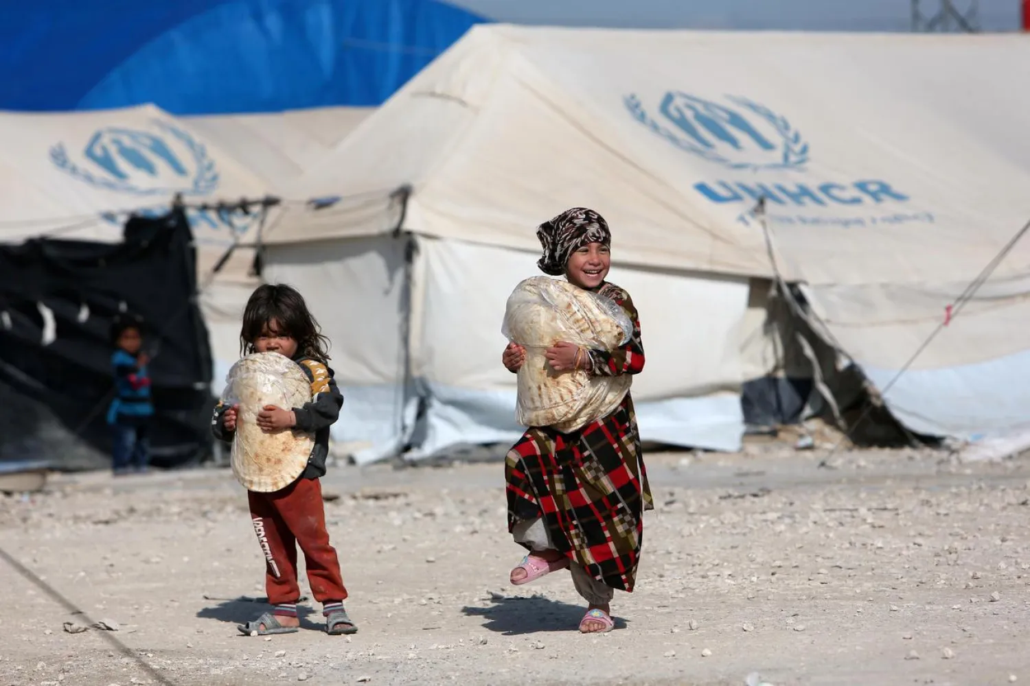 Children holding stacks of bread walk in al-Hol displacement camp in Hasaka governorate, Syria, April 2, 2019. REUTERS/Ali Hashisho/File Photo