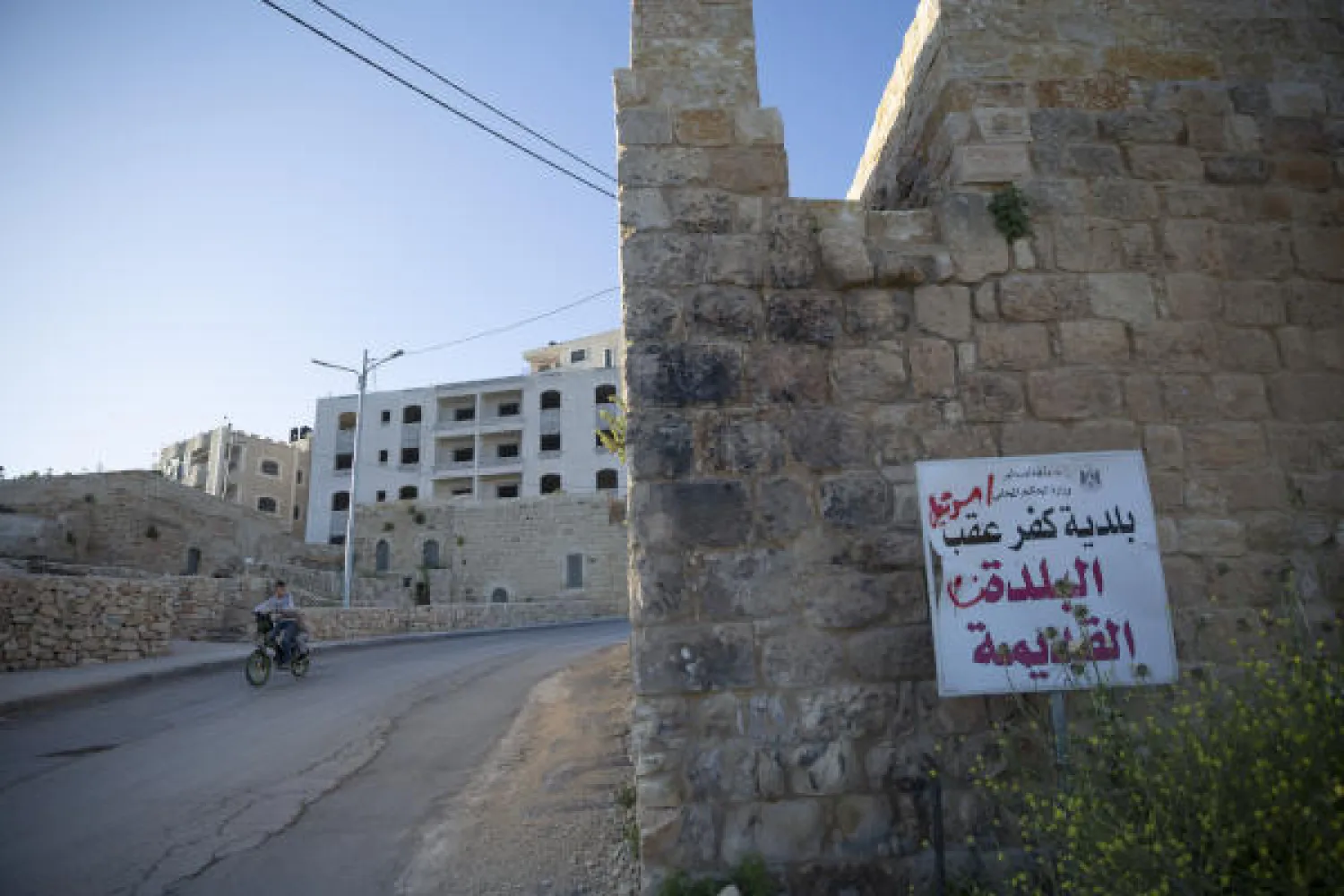 In this Tuesday, April 28, 2020 photo, a sign in Arabic reads "the old town, the municipality of Kufr Aqab, ministry of local government, the state of Palestine," on a road in the West Bank village of Kufr Aqab. AP