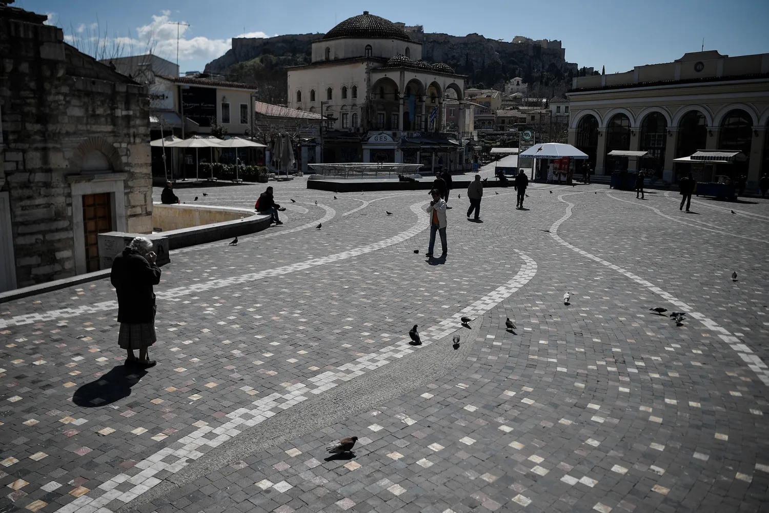 People walk across the empty Monastiraki square under the
Acropolis in central Athens, on March 18. Photographer: Louisa
Gouliamaki/AFP via Getty Images
