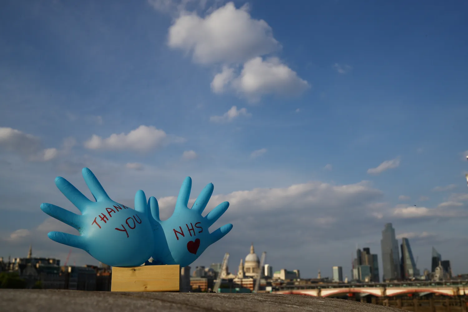 قفازان عملاقان عليهما عبارة شكر للخدمات الصحية الوطنية على ضفة نهر التيمز في لندن (رويترز)