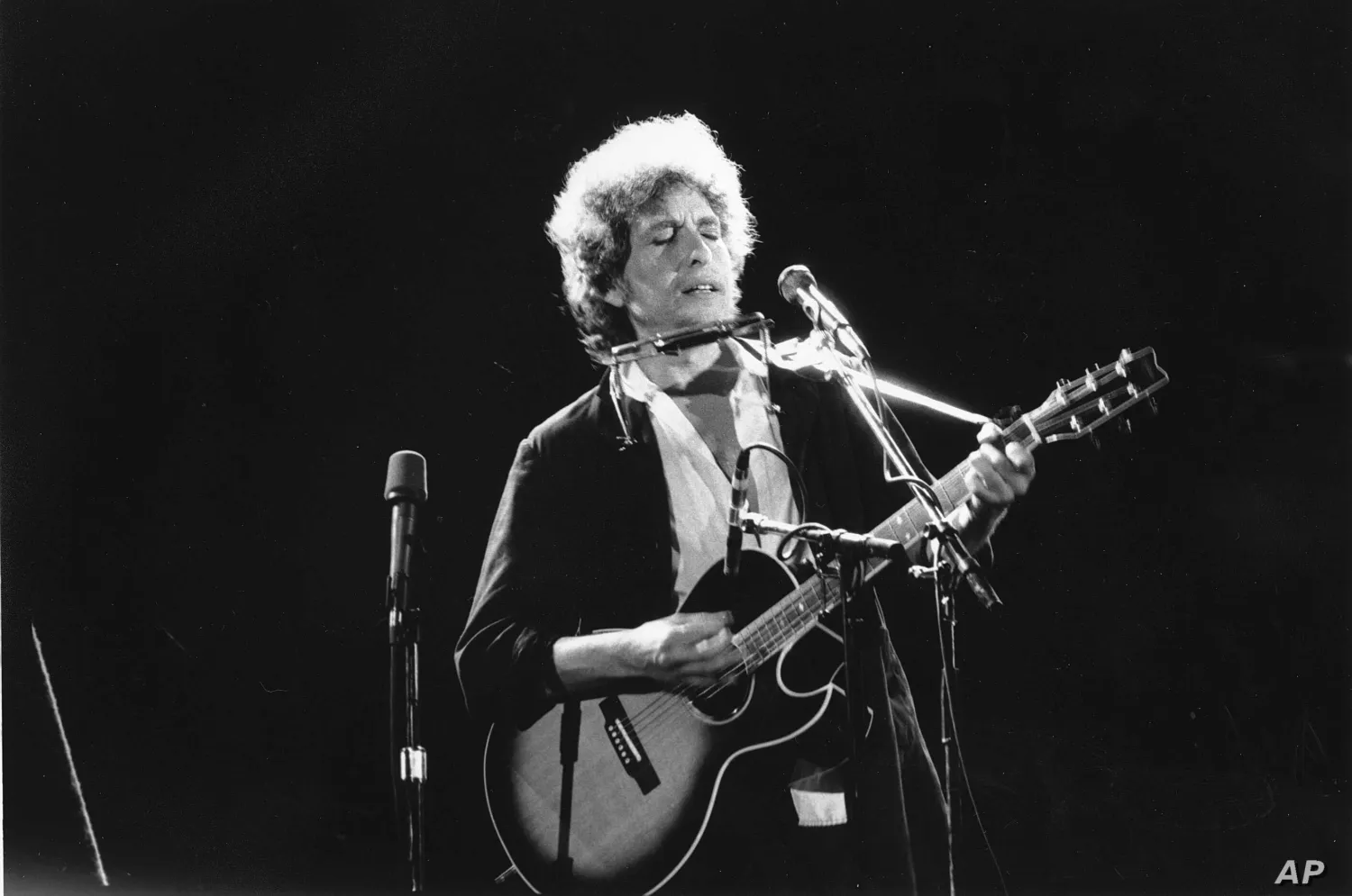 FILE - Singer-songwriter Bob Dylan as he plays his acoustic
guitar with his harmonica.