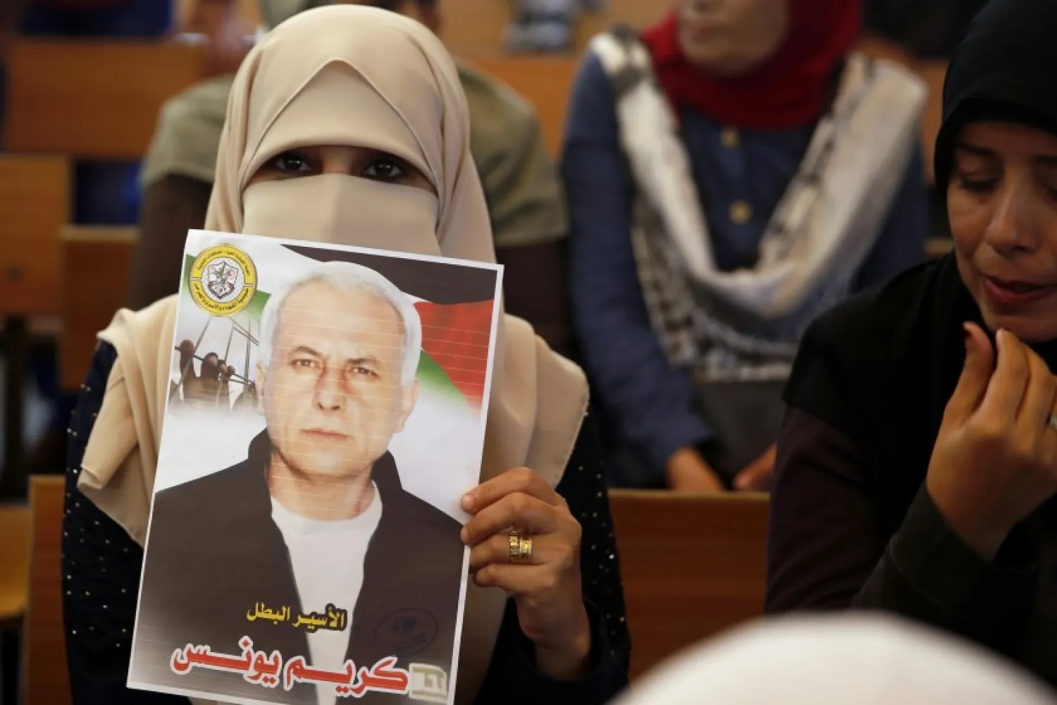 In this Oct. 28, 2019, file photo, a Palestinian woman holds a portrait of a relative being held in an Israeli jail as they demonstrate for prisoner release, in front of the International Committee of the Red Cross, in Gaza City.(AP Photo/ Hatem Moussa, File)