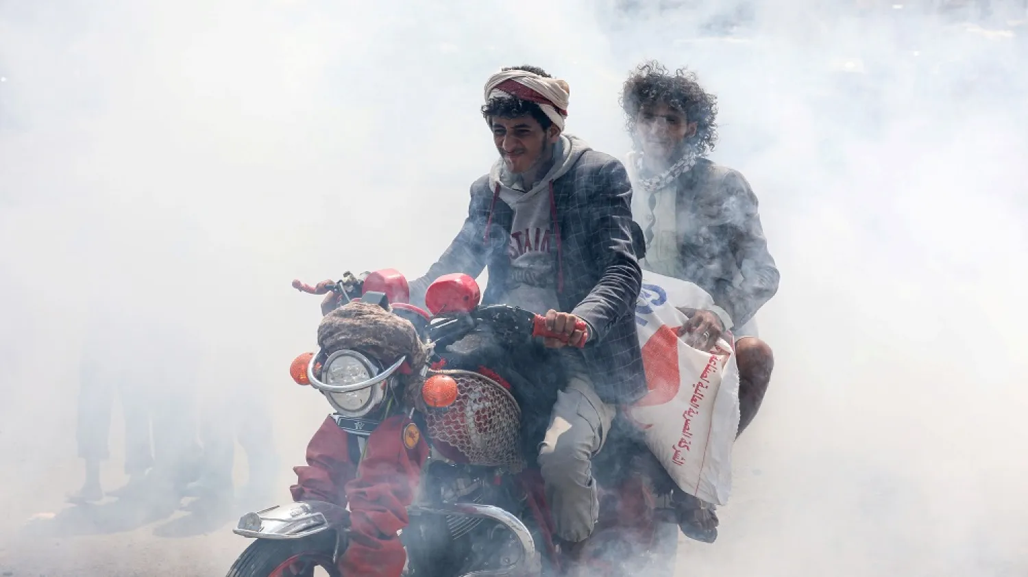 People ride a motorbike through smoke during fumigation to stop the spread of the coronavirus in the outskirts of Sanaa, Yemen. (Reuters)