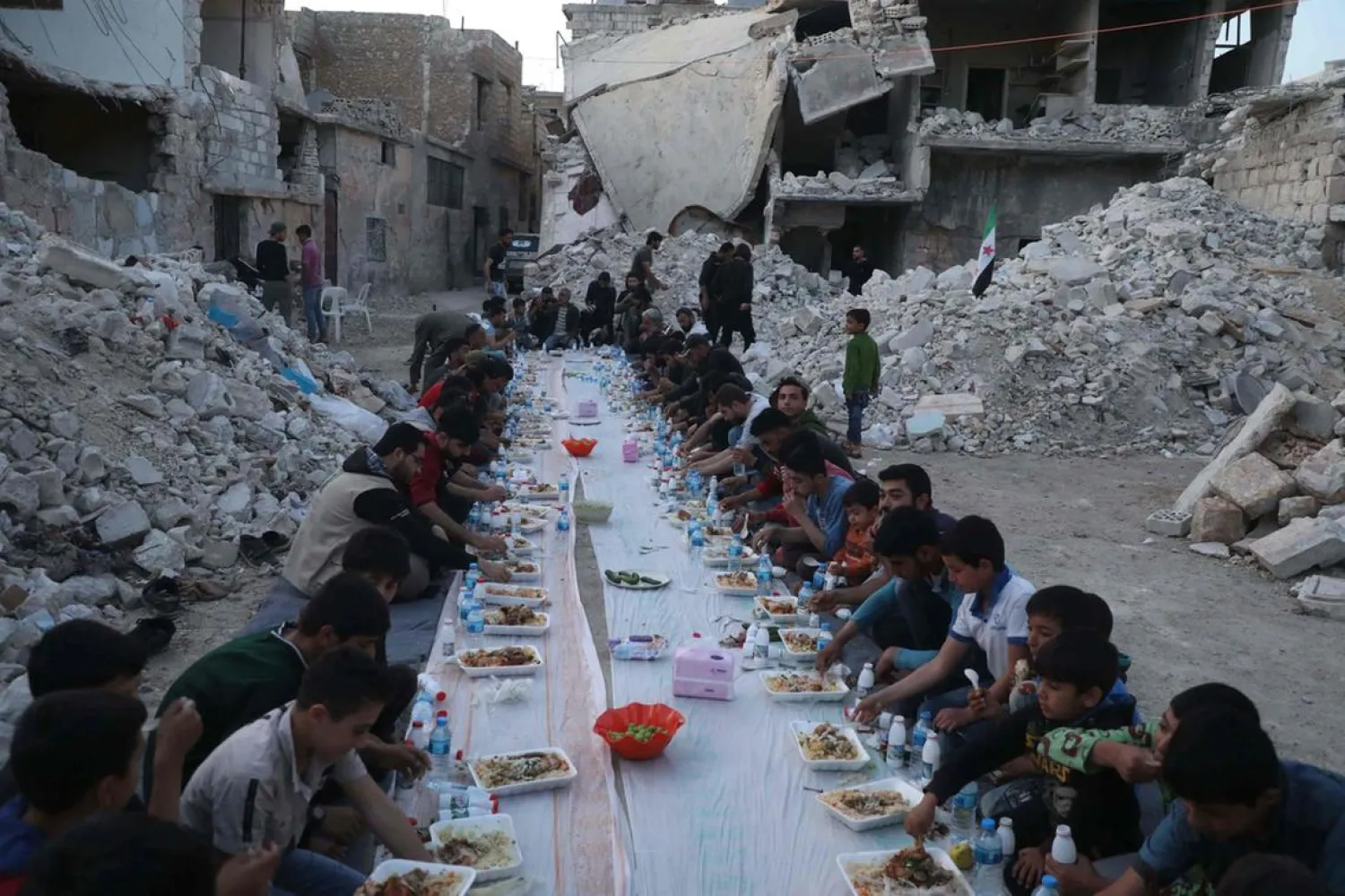 Syrian residents gather at sunset to share the iftar meal amidst the rubble of a destroyed neighborhood in Atareb town in the opposition-held western countryside of Syria's Aleppo province. (AFP)