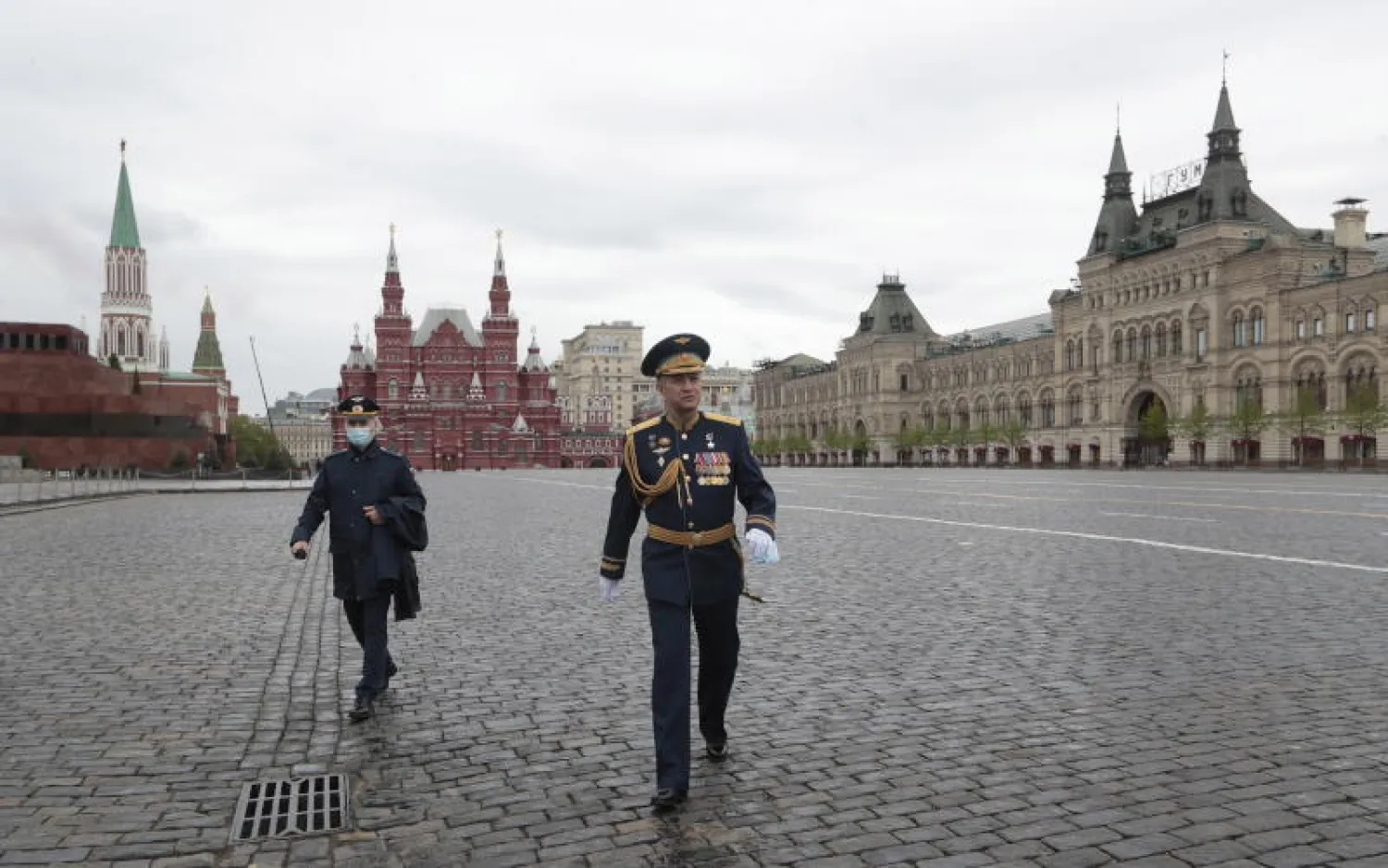 عسكريان روسيان يسيران في الساحة الحمراء الخالية بعد تقليص الاحتفالات عيد النصر بسبب فيروس كورونا (إ.ب.أ)