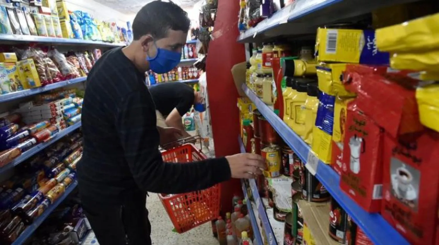 Maske takmış bir Cezayirli alışveriş yapıyor (AFP)