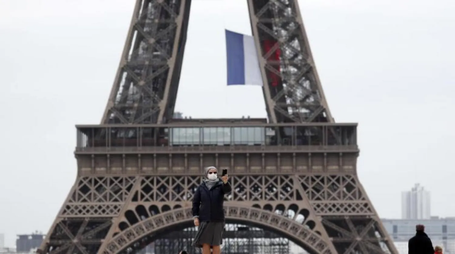 Fransa’nın başkenti Paris’te Eyfel Kulesi önünde selfie çeken maskeli bir kadın (EPA)