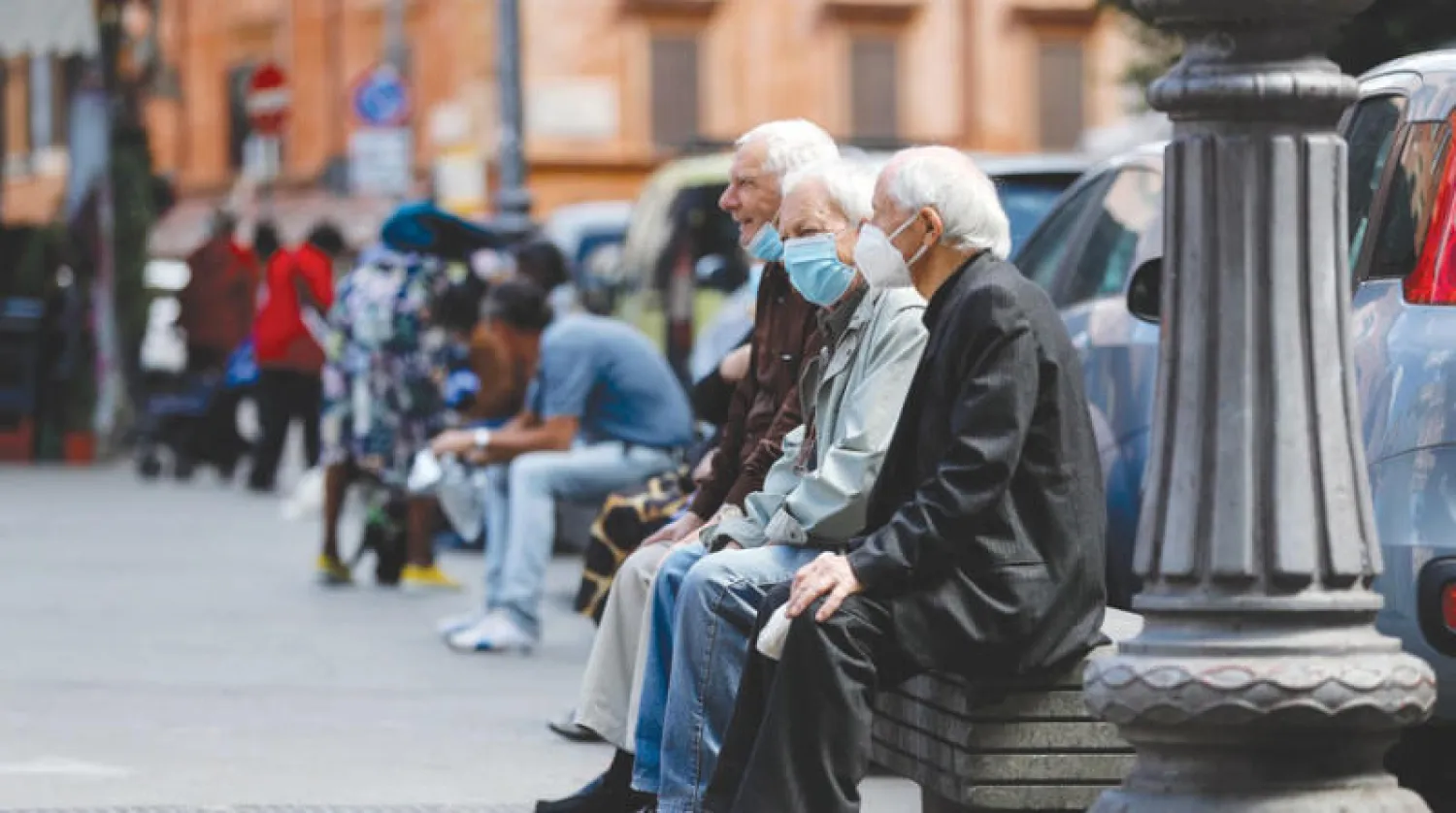 مسنون يضعون كمامات للوقاية من «كورونا» في ضاحية تراستيفيري بالعاصمة الإيطالية روما أمس (إ.ب.أ)