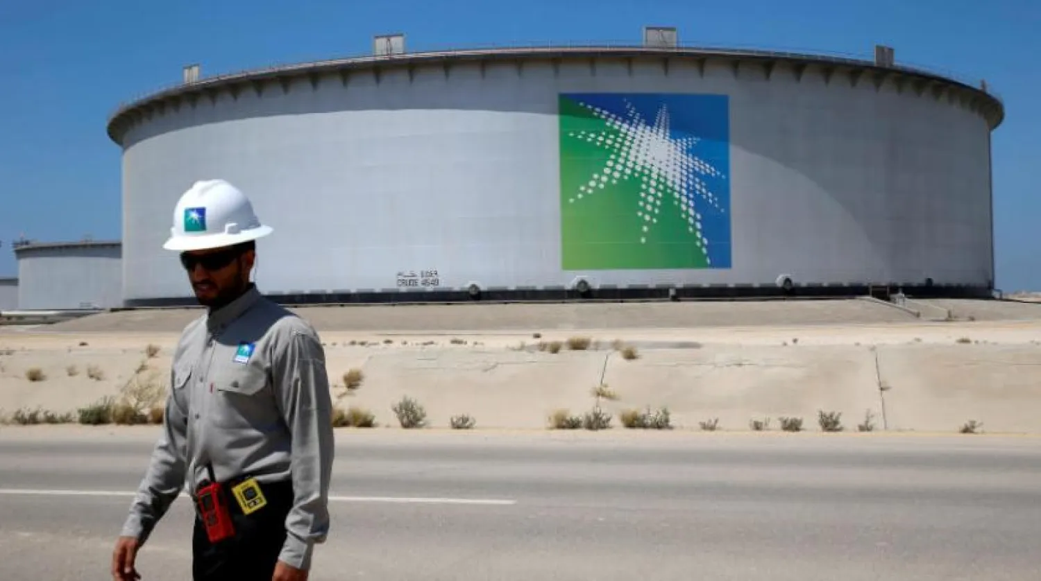 Ras Tanura Petrol Rafinerisi’ndeki bir petrol tankının yakınında yürüyen bir Saudi Aramco çalışanı (Reuters)