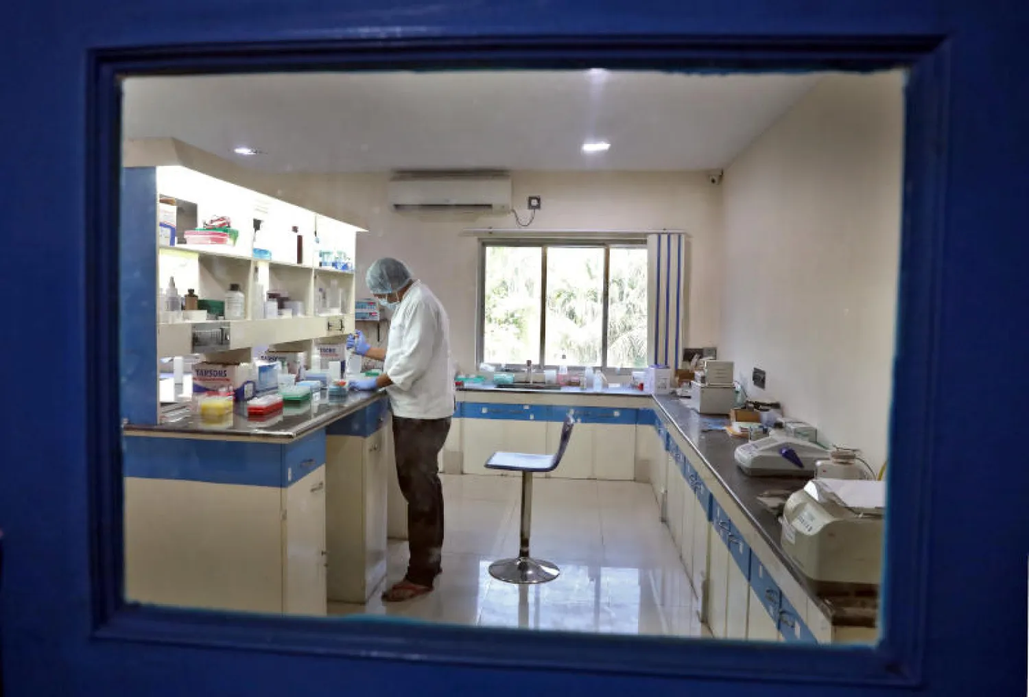 عالم يفحص مجموعة عينات خلال عمله على اختبارات لمكافحة «كورونا» (رويترز)