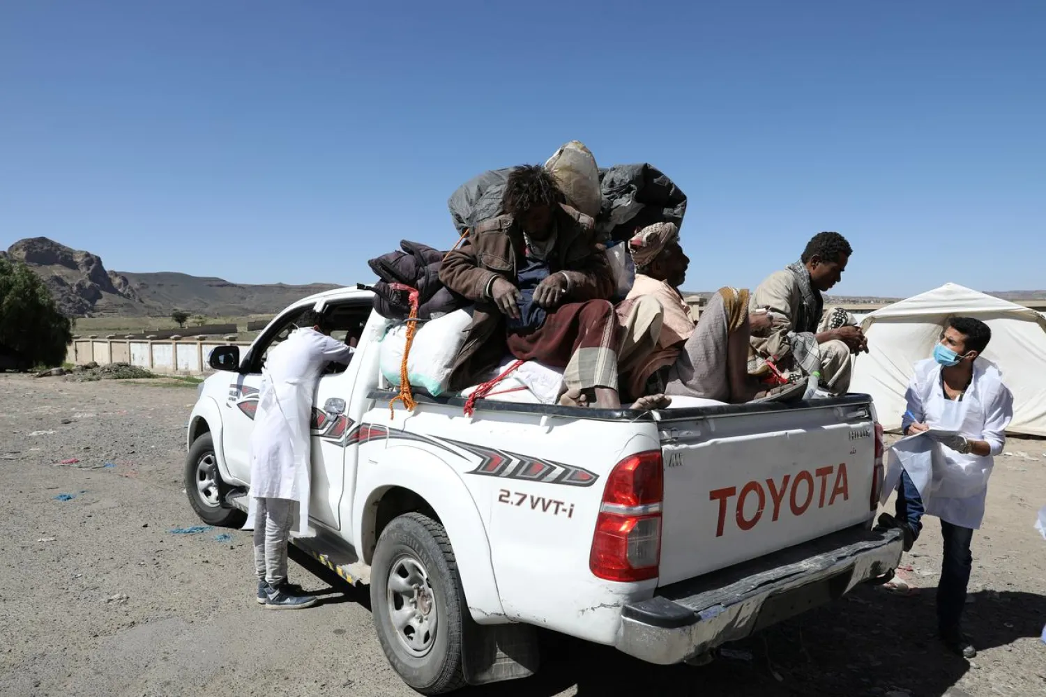 Health workers take temperature and info of people riding on a truck, amid concerns of the spread of the coronavirus, at the main entrance of Sanaa, Yemen May 9, 2020. (Reuters)