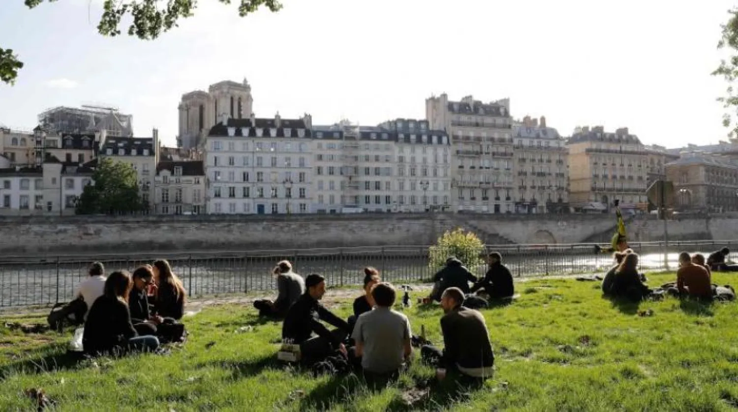 Paris'te Seine Nehri kıyısında oturan insanlar (AFP)