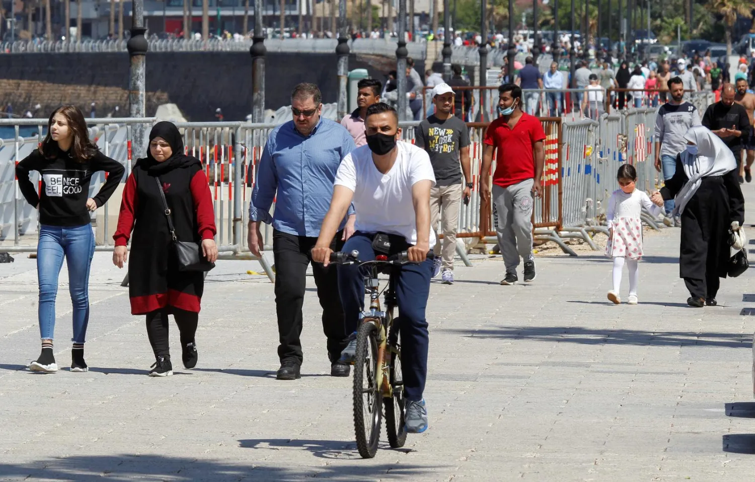 People walk and a man rides a bicycle along Beirut's seaside Corniche after the government eased some restrictions on public life, in Beirut, Lebanon May 10, 2020. (Reuters)