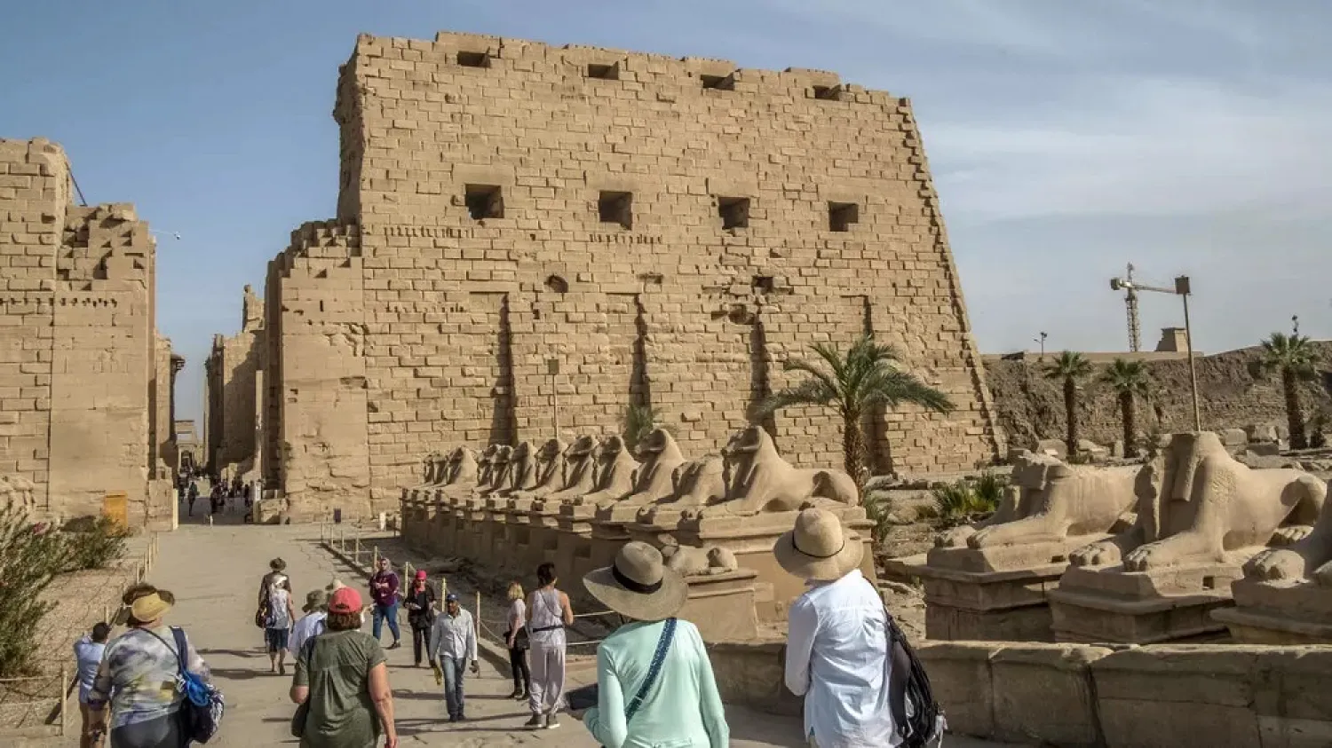 Tourists stroll along the avenue of the ram-headed sphinxes, symbolizing the ancient Egyptian god Amun, at the Karnak temple complex in Egypt's southern city of Luxor. (AFP)