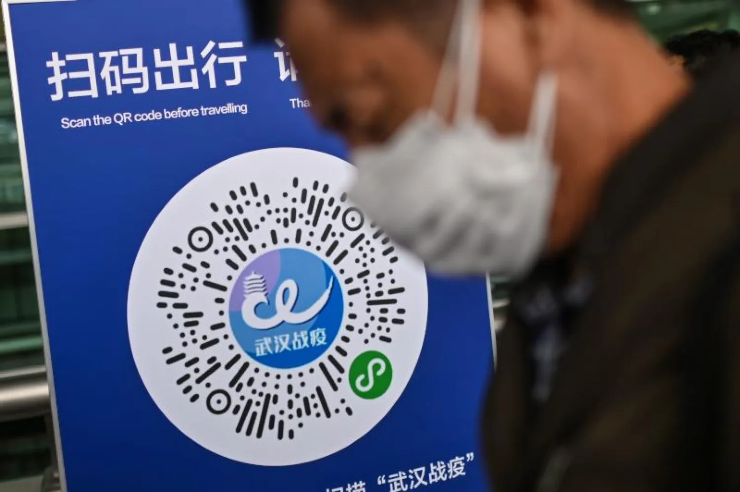 مواطن صيني أمام لافتة لأحد التطبيقات التي ترصد «كورونا» في ووهان (أ.ف.ب)