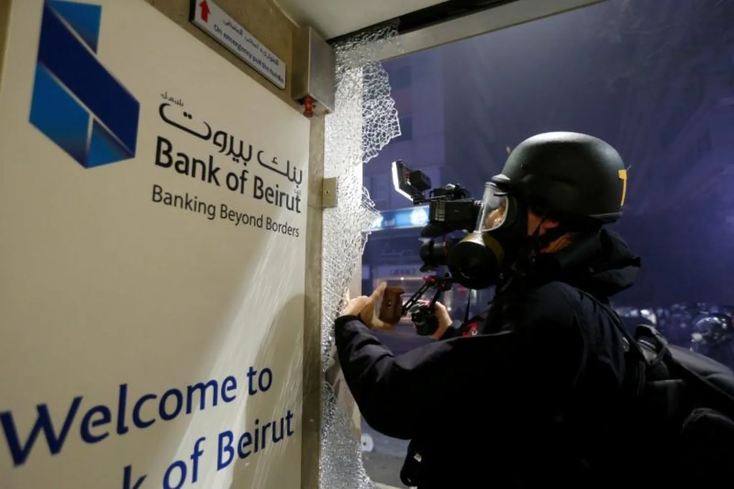 FILE PHOTO: A man films a damaged window of a bank which was shattered during protests against the economic crisis in Beirut, Lebanon January 14, 2020. REUTERS/Mohamed Azakir/File Photo