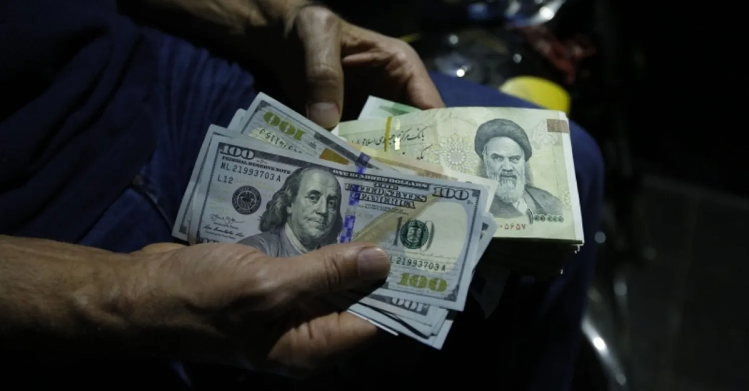 In this file photo taken on Aug. 8, 2018, a man holds Iranian rials and US dollars at an exchange shop in the Iranian capital Tehran. (AFP)