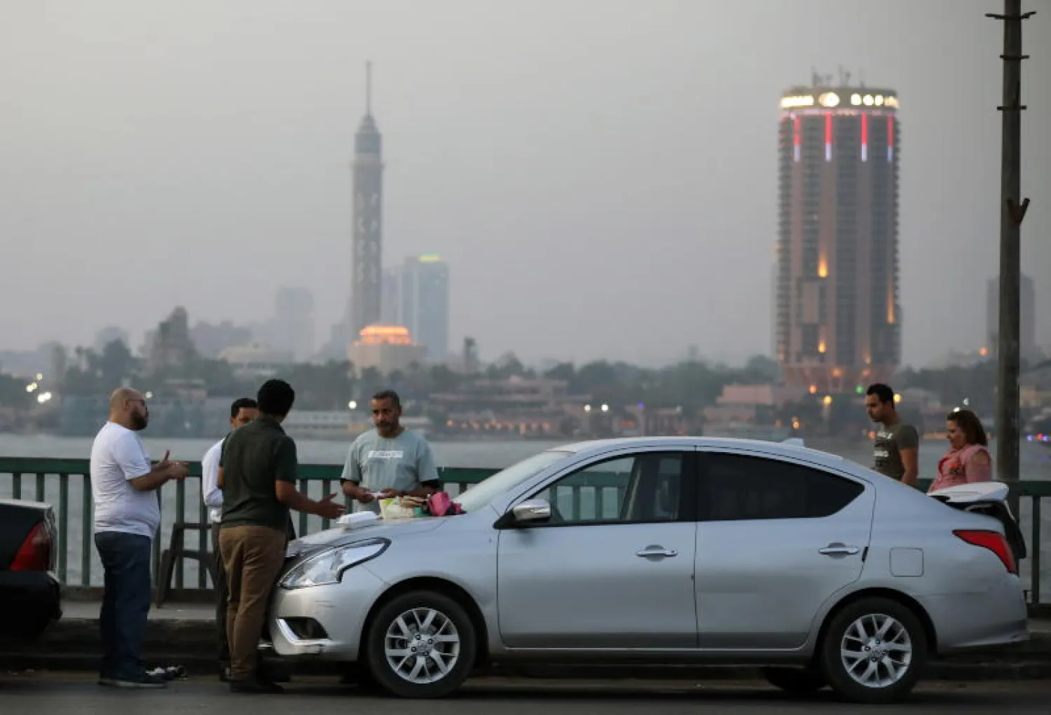 مصريون يتناولون طعام الإفطار على كوبري جامعة القاهرة فوق النيل (إ.ب.أ)