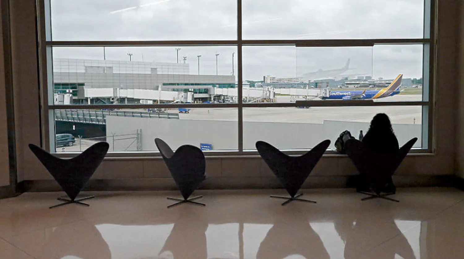 مسافرة تراقب مدرج مطار دالاس من قاعة انتظار شبه خالية (إ.ب.أ)