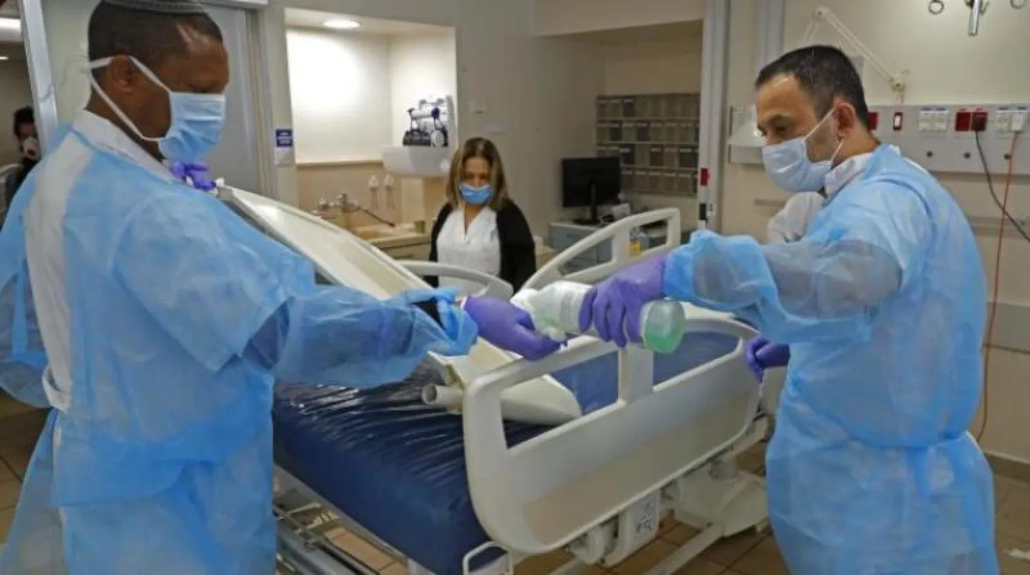 فريق طبي يقوم يتعقيم غرفة مخصصة لعلاج المصابين بفيروس كورونا في تل أبيب (أ.ف.ب)