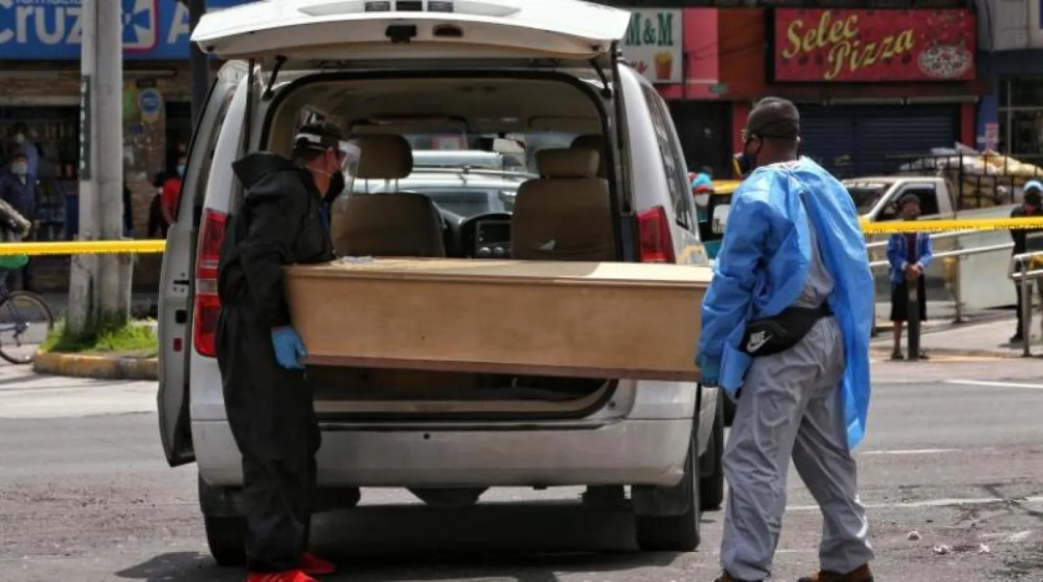 Ekvador'un başkentinde görevliler koronavirüs kurbanının cesedini taşıyor (AFP) 
