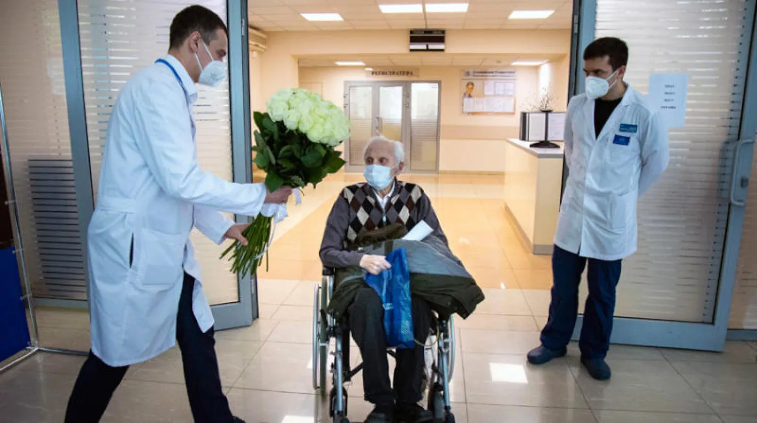 طبيب روسي يهنّئ مواطنا عمره 100 عام تعافى من كورونا بموسكو أمس (أ.ب)