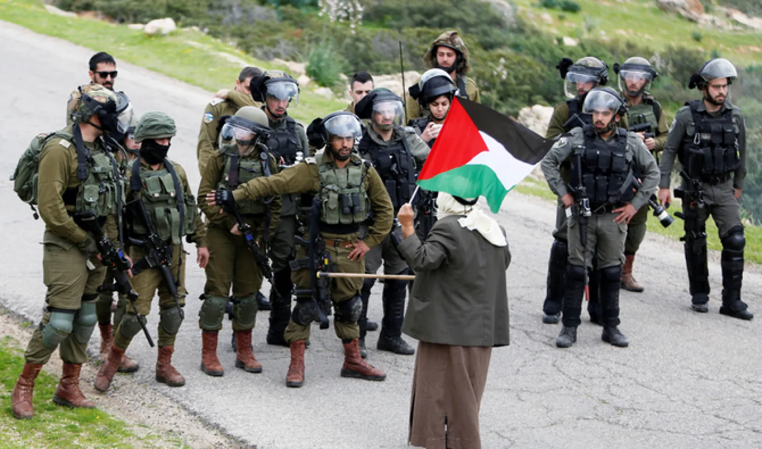 A demonstrator holding a Palestinian flag stands in front of Israeli forces during a protest against Israeli settlements and the US President Donald Trump's Middle East peace plan, in Jordan Valley in the Israeli-occupied West Bank on February 25, 2020. Reuters